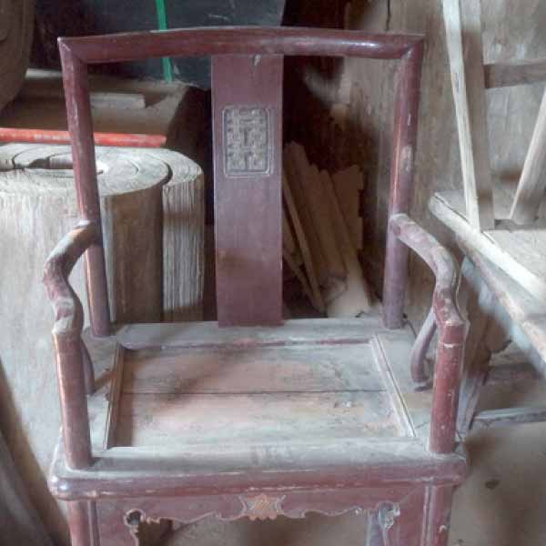 Un fauteuil ancien en bois, poussiéreux et abîmé au niveau de l'assise.