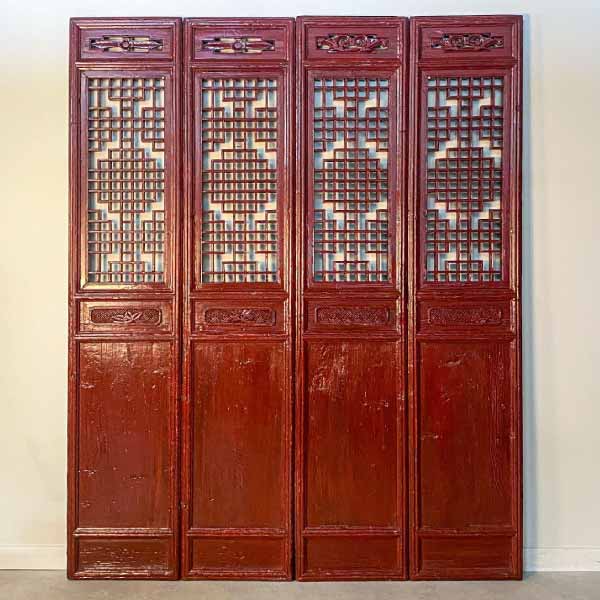 Quatre portes chinoises rouges, rénovées, laquées, côte à côte. Elles sont ajourées et présentent un très élégant et graphique travail du bois.