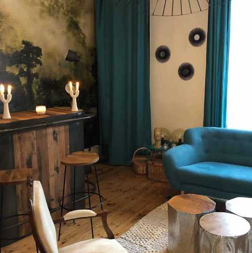 Espace d'accueil d'une maison d'hôtes de Daoulas : bar industriel, canapé bleu et tables basses en teck et étain (service aux professionnels Rue de Siam)
